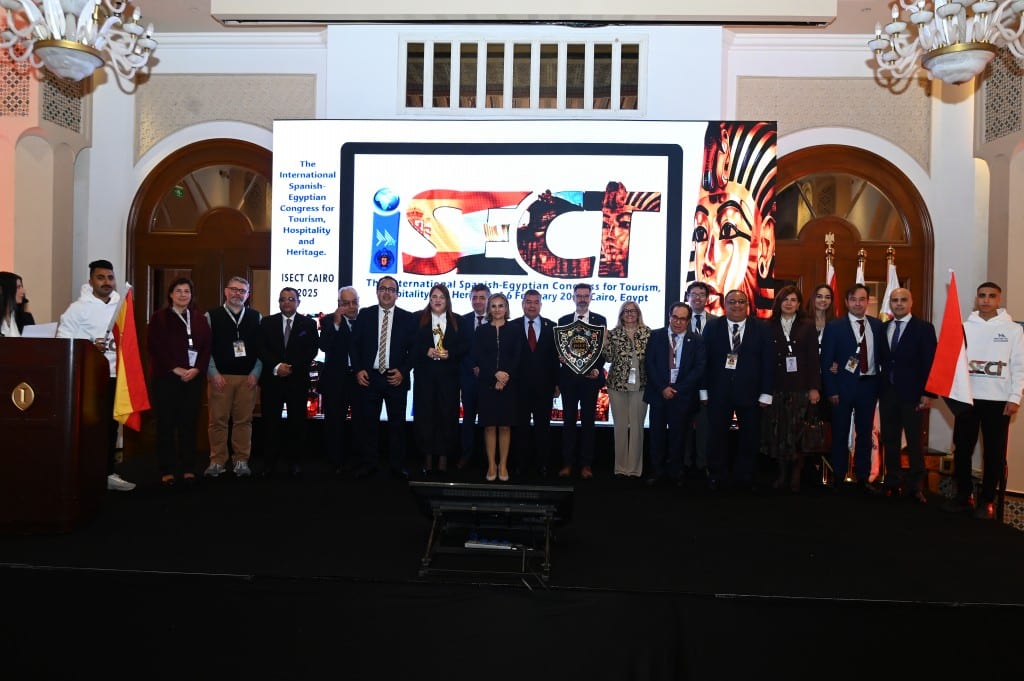 A long line of delegates stands across a stage in front of a large lit screen, national flags at either end.