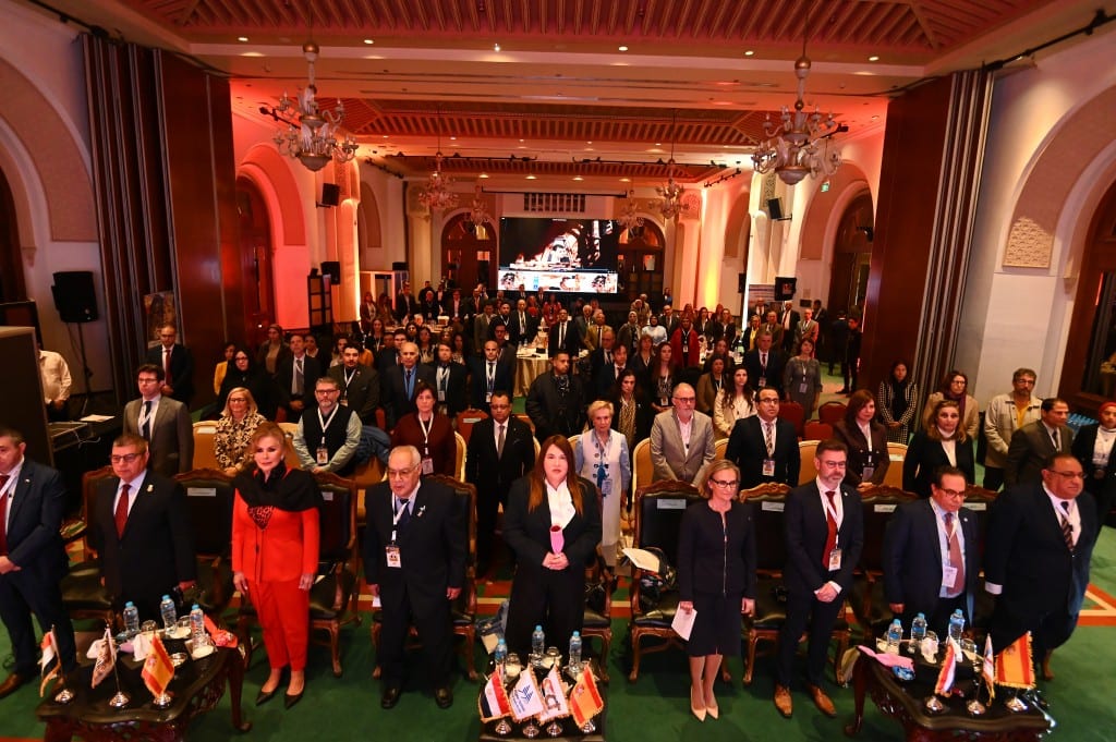 A packed ballroom of delegates stands at their round tables at the start of proceedings.