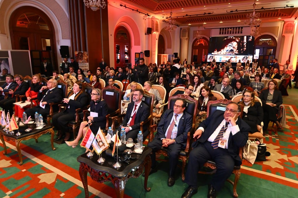 Delegates fill the front rows of the hall, small national flags on the tables in front of them.